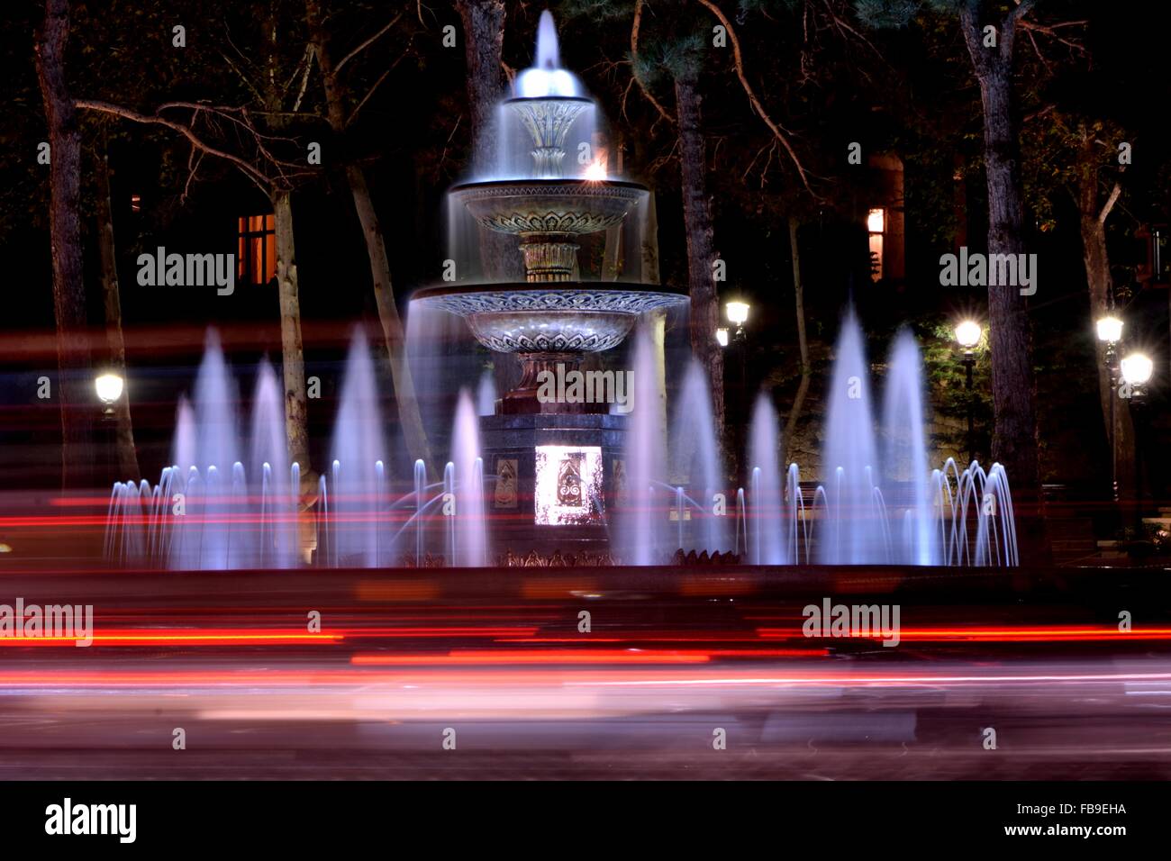 Fountain at night in park in Baku, capital of Azerbaijan. A night scene showing water in a fountain and light trails from cars Stock Photo