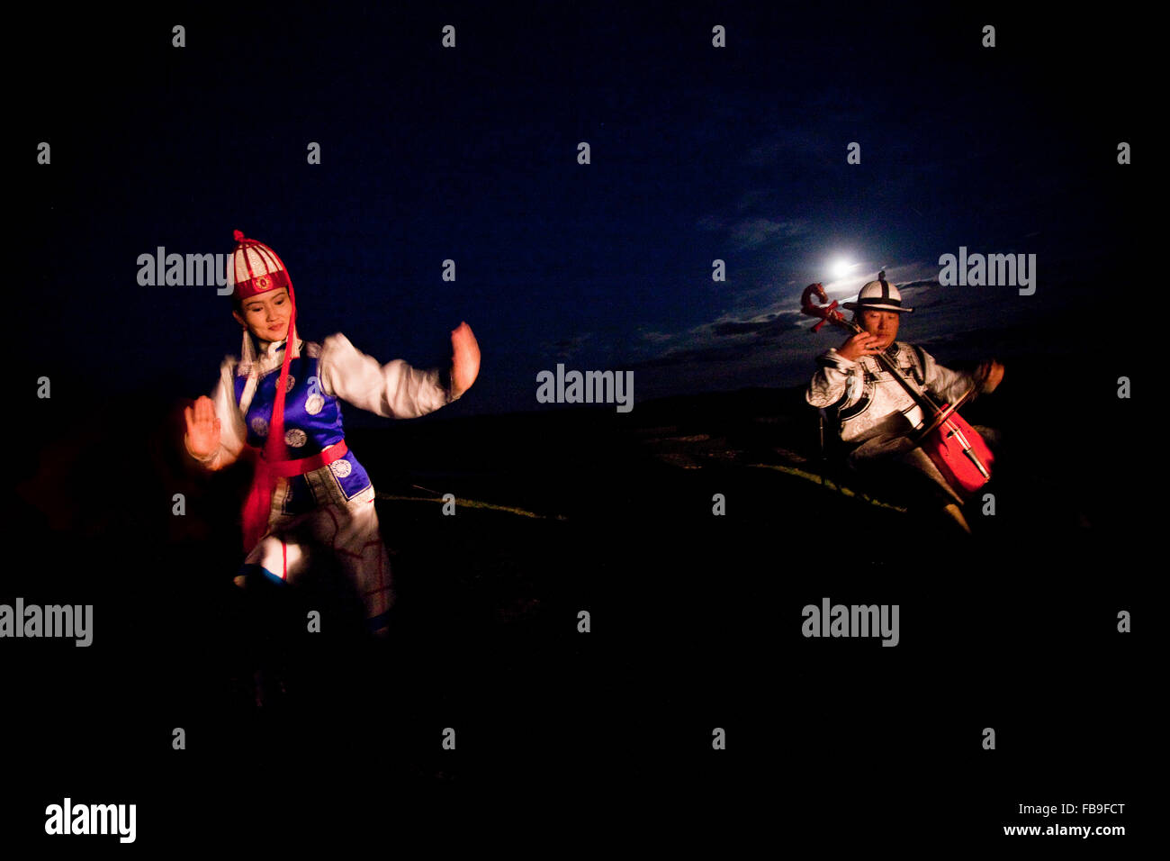 Throat singing, flute, horse hair fiddle and dancing convey the rhythms of horses and steppe life in the moonlight, Mongolia. Stock Photo
