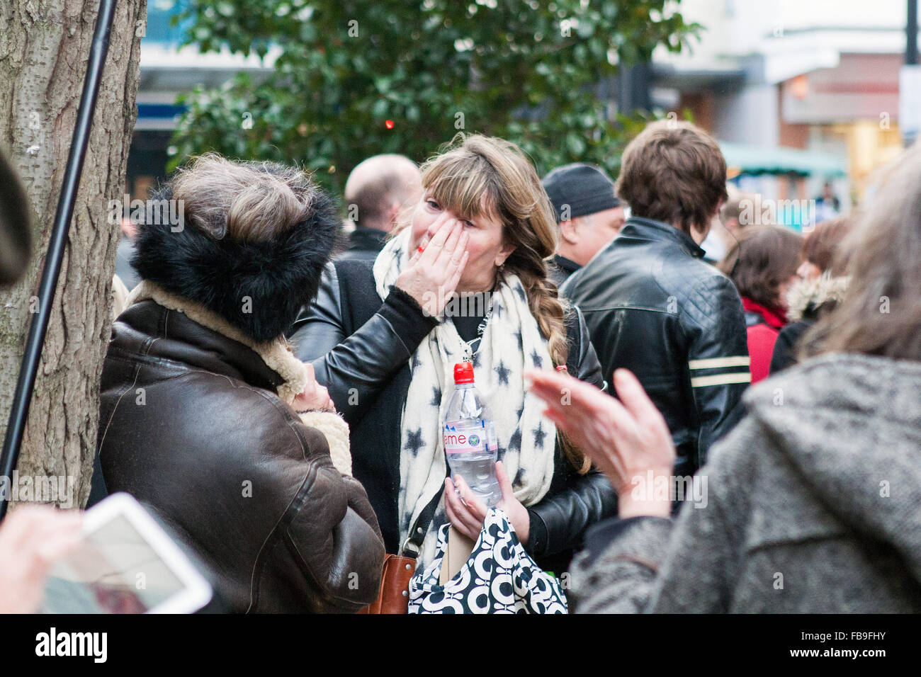 London, UK. 12th January, 2016. Fan wiping away tears as tributes and messages from others lie beneath a mural of the late David Bowie. Brixton Underground station, London, UK. © martyn wheatley/Alamy Live News Stock Photo