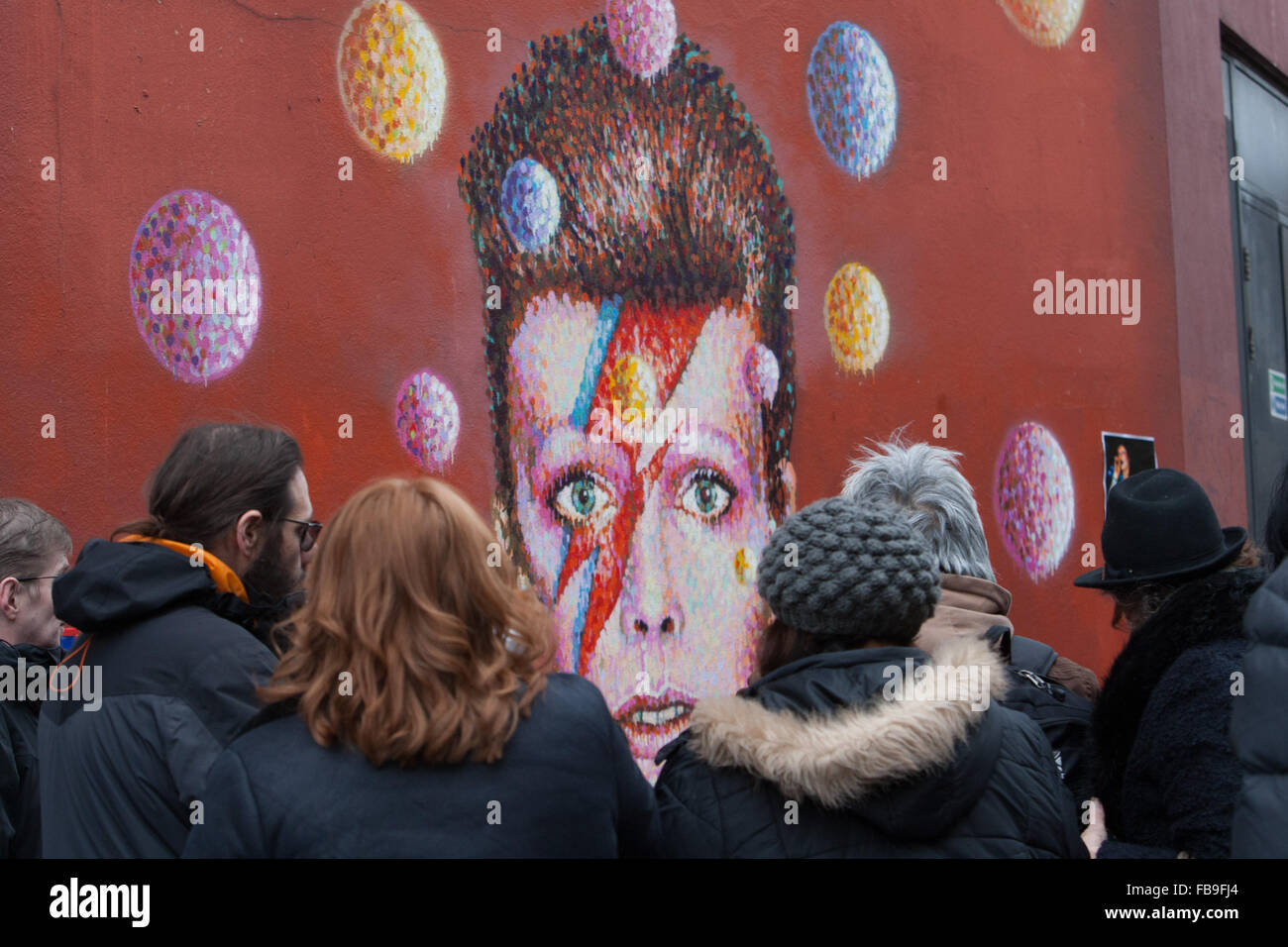 Tributes and messages from fans lie beneath a mural of the late David Bowie Brixton Underground station, London, UK. © martyn wheatley/Alamy Live News Stock Photo