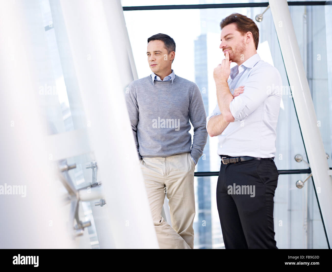 two caucasian business people looking out of window Stock Photo