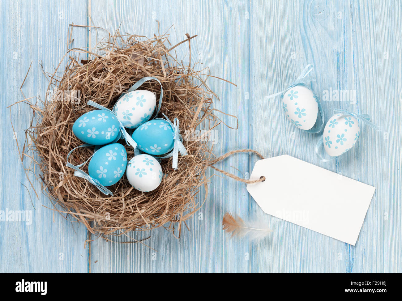 Easter card with eggs in nest on blue wooden table. Top view with copy ...