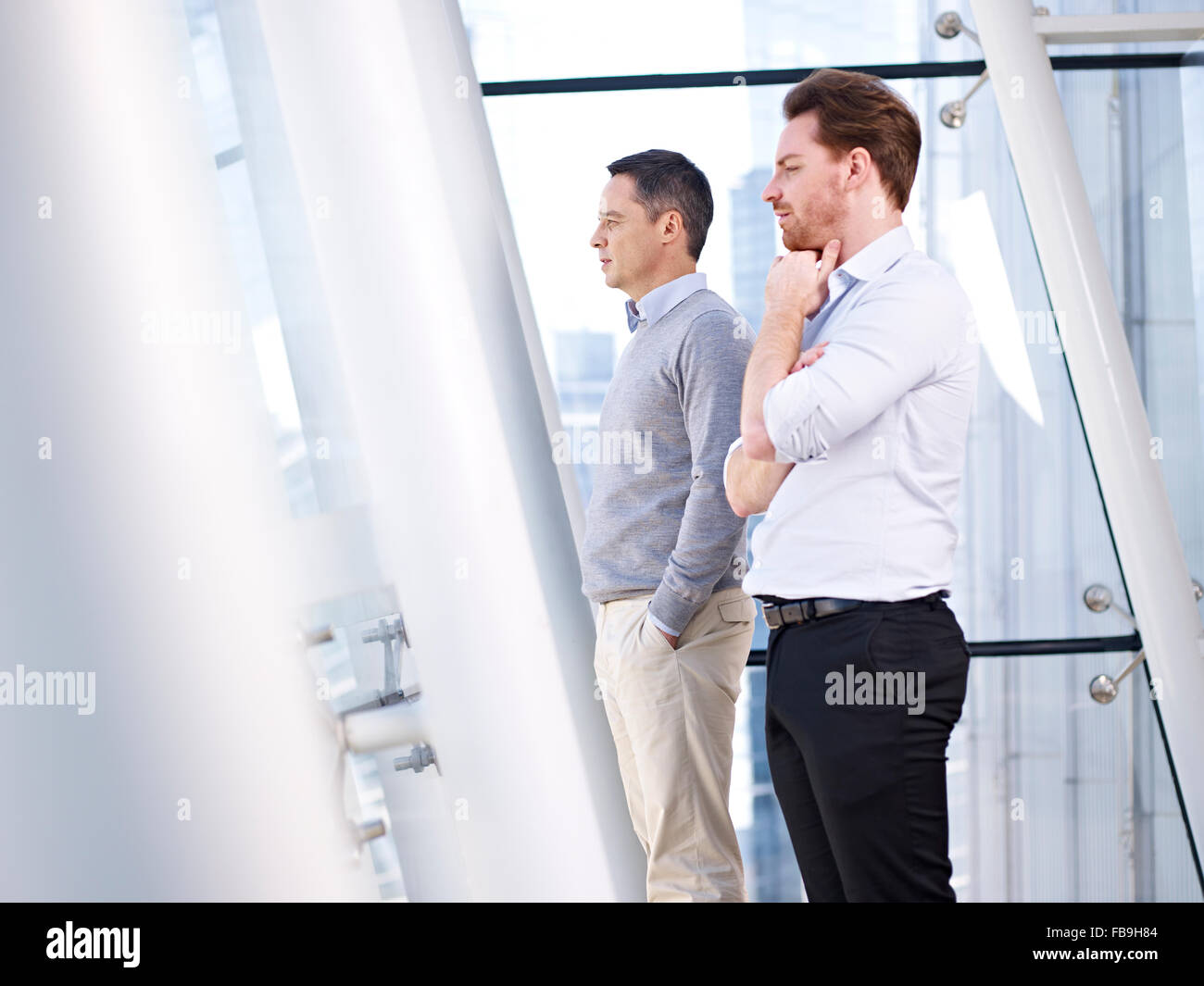 two caucasian business people looking out of window Stock Photo