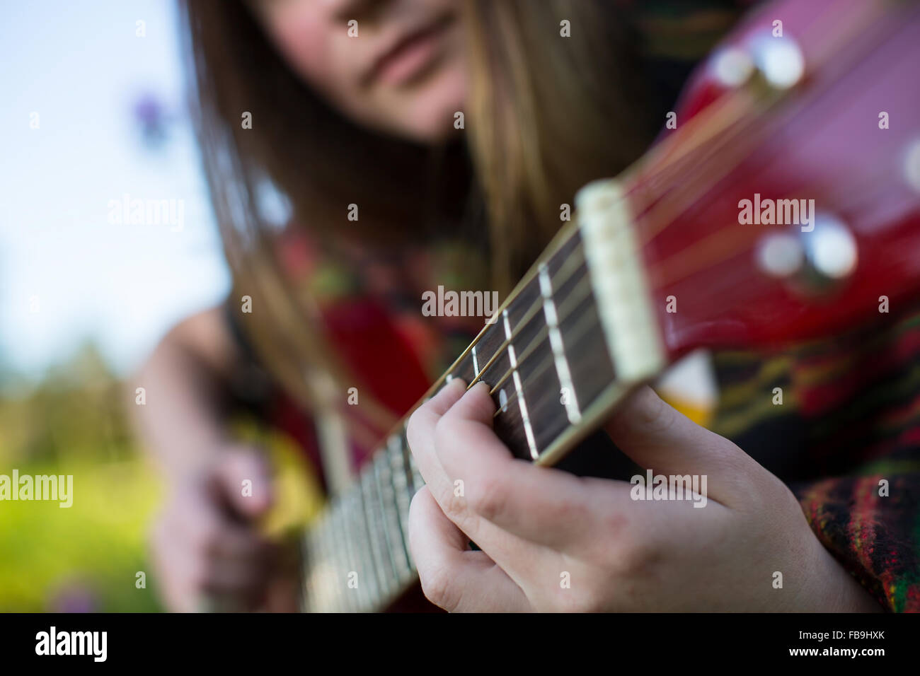 Fingers on the strings close-up, young girl plays on the acoustic guitar. Stock Photo