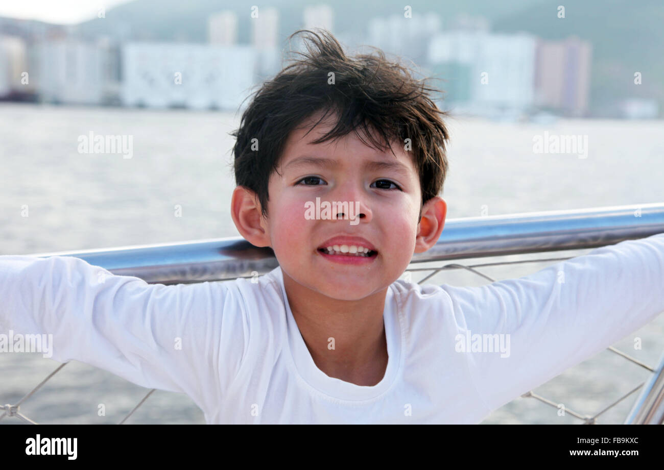 It's a photo of a 5 years old Asian boy posing near the sea view Stock Photo