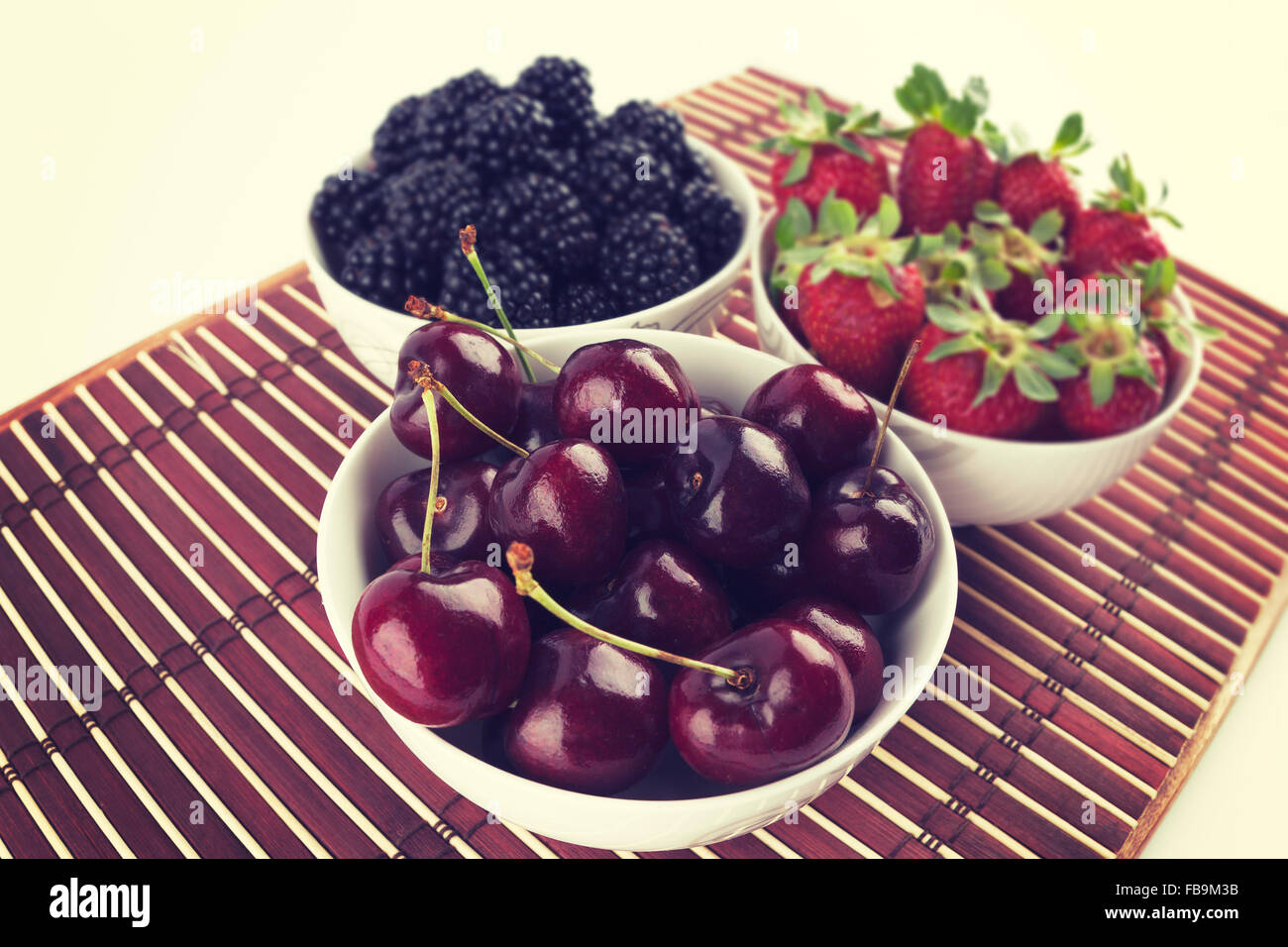 Closeup of bowl with cherries with strawberries and blackberries in the