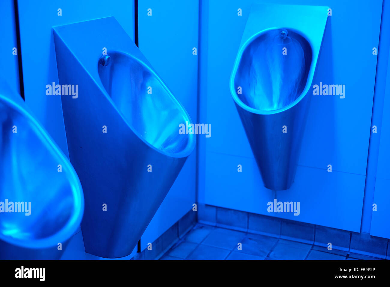Blue lighting in mens urinals to prevent the use of needles by addicts. Stock Photo