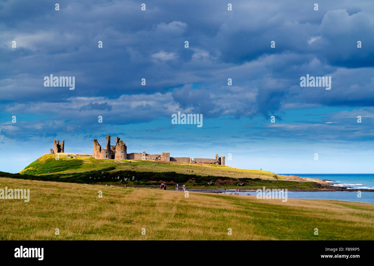 Ruins of Dunstanburgh Castle in Northumberland north east England UK with Embleton Bay and the north sea visible beyond Stock Photo