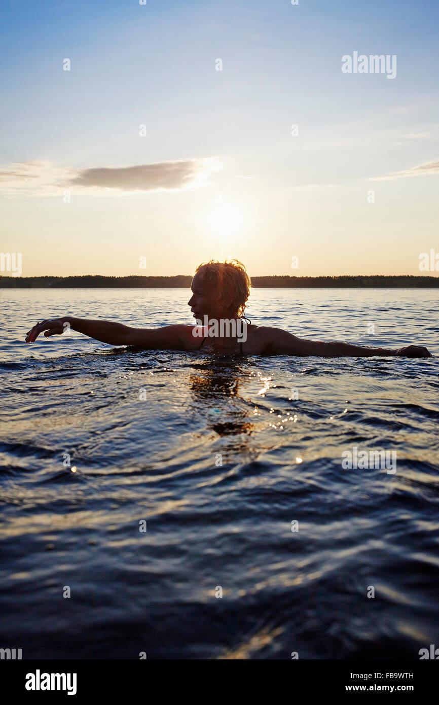 Sweden, Vastra Gotaland, Skagern, Woman swimming in lake Stock Photo