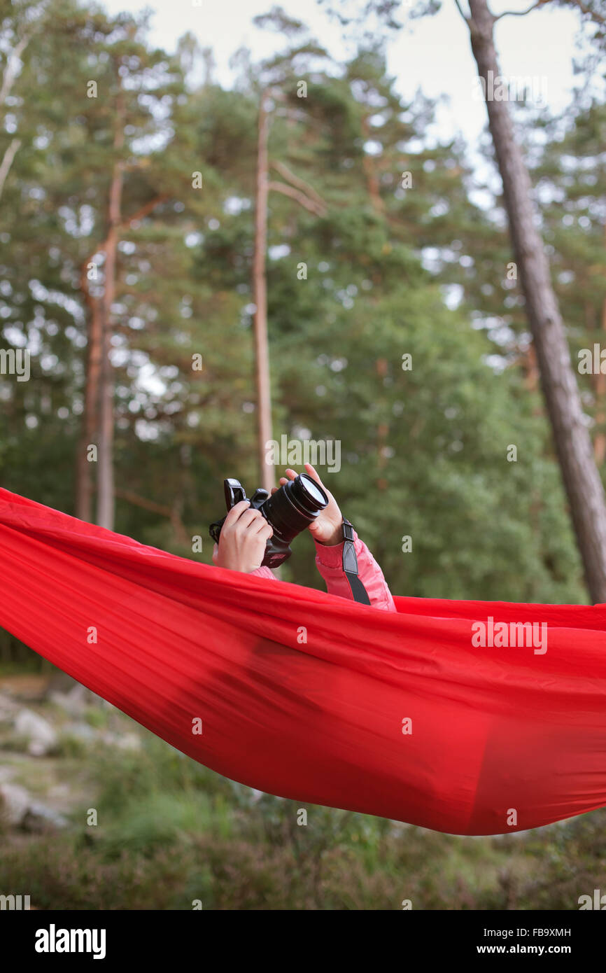 Sweden, Vastergotland, Lerum, Girl (10-11) lying in hammock and taking pictures with camera Stock Photo