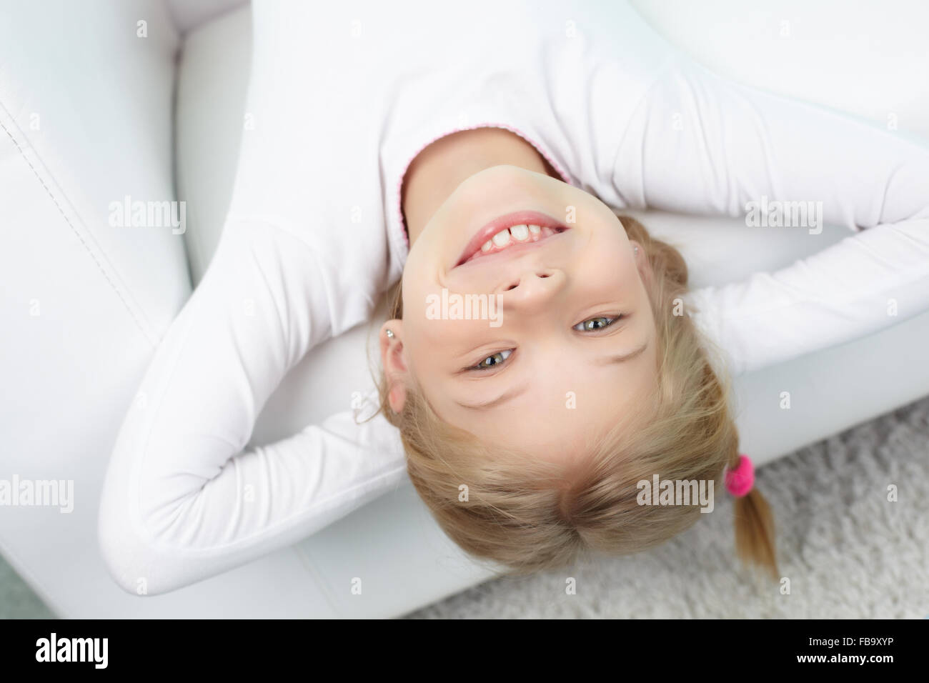Beautiful little girl lying on sofa and smiling Stock Photo - Alamy