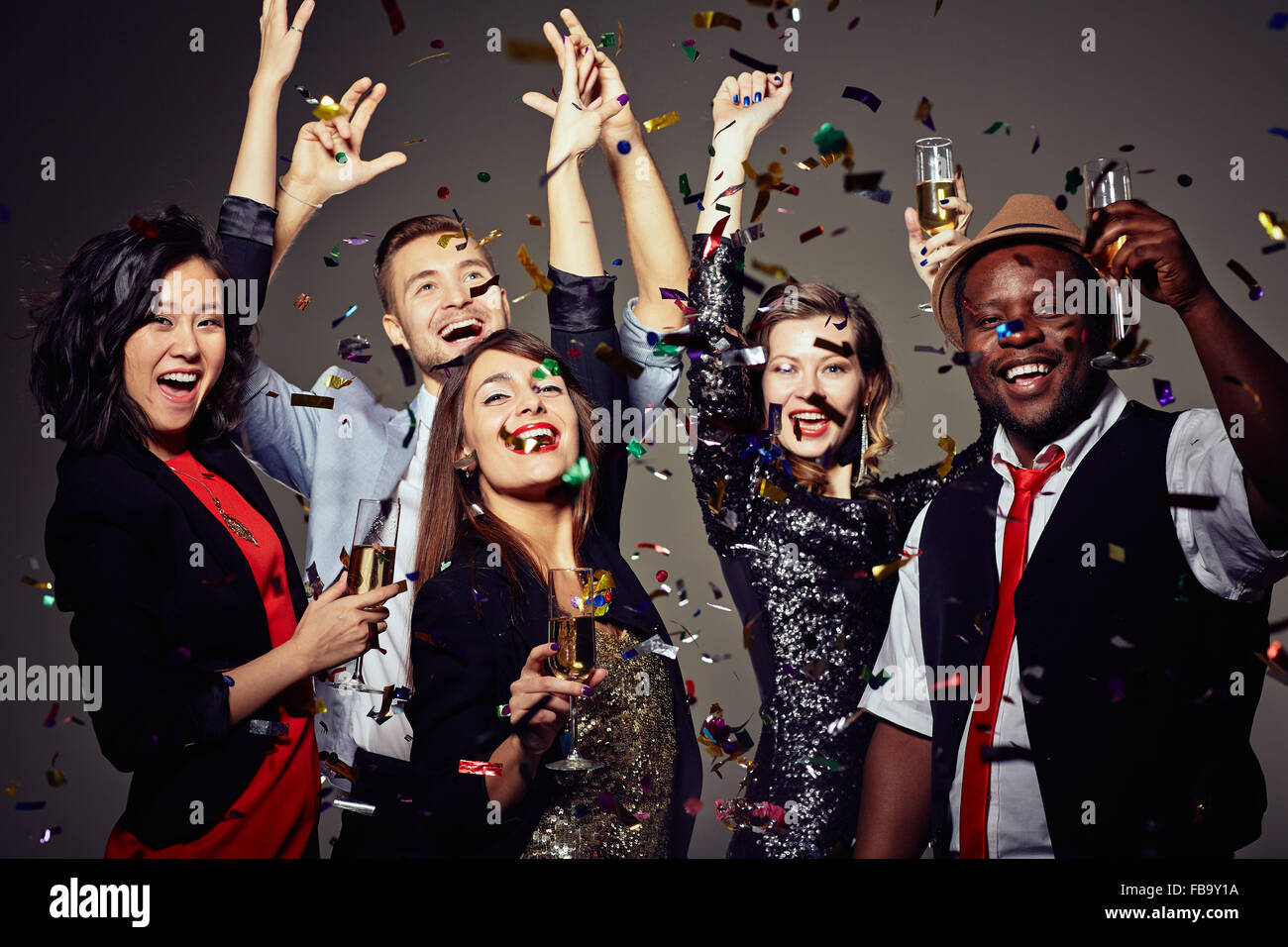 Group of happy smiling friends having fun together among confetti in night club Stock Photo