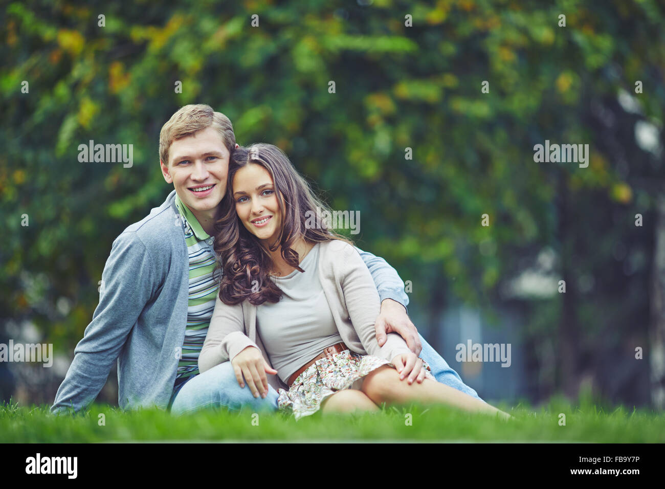 Young lovely couple sitting on grass outdoors Stock Photo - Alamy