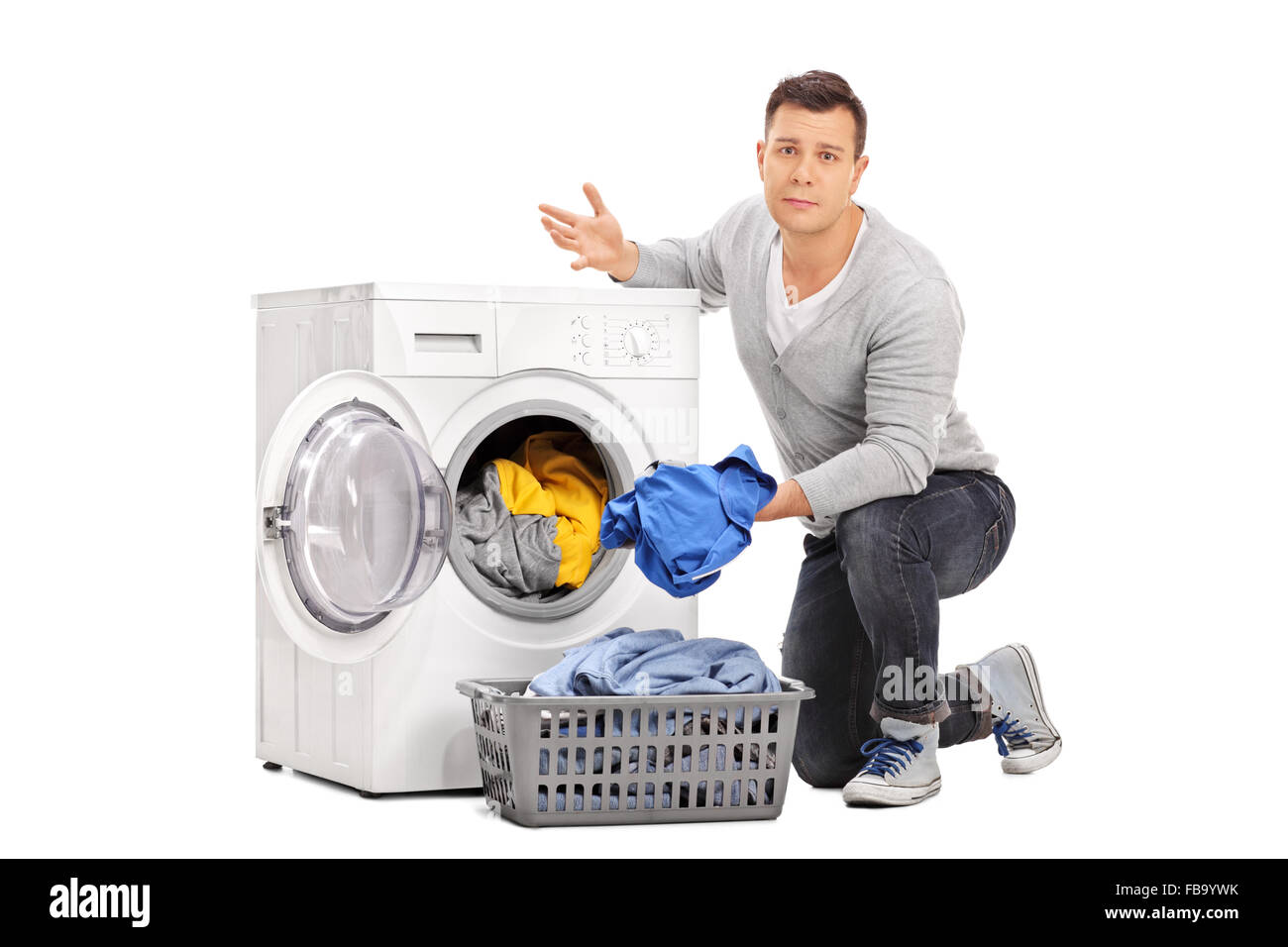 Sad young guy emptying a washing machine isolated on white background Stock Photo