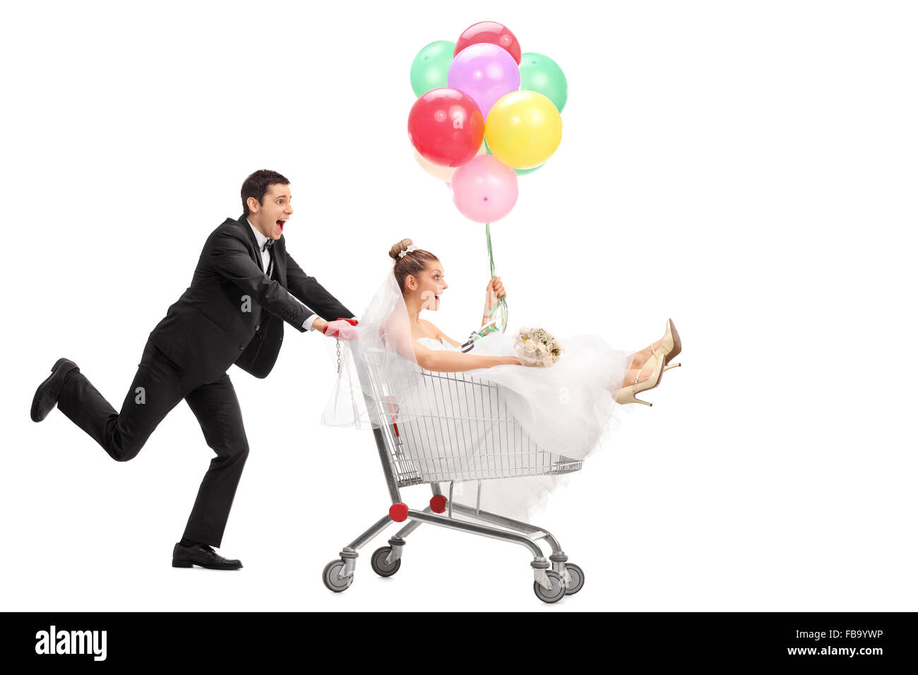 Studio shot of a newlywed couple driving in a shopping cart isolated on white background Stock Photo