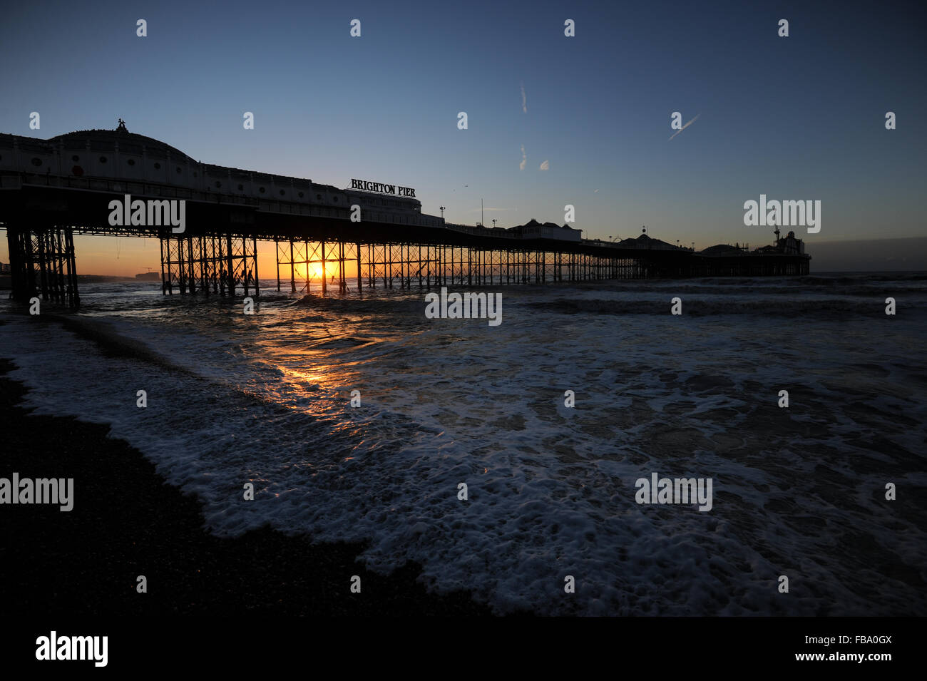 Brighton Pier is silhouetted against a beautiful sunrise on the beach in Brighton, East Sussex, UK. Stock Photo