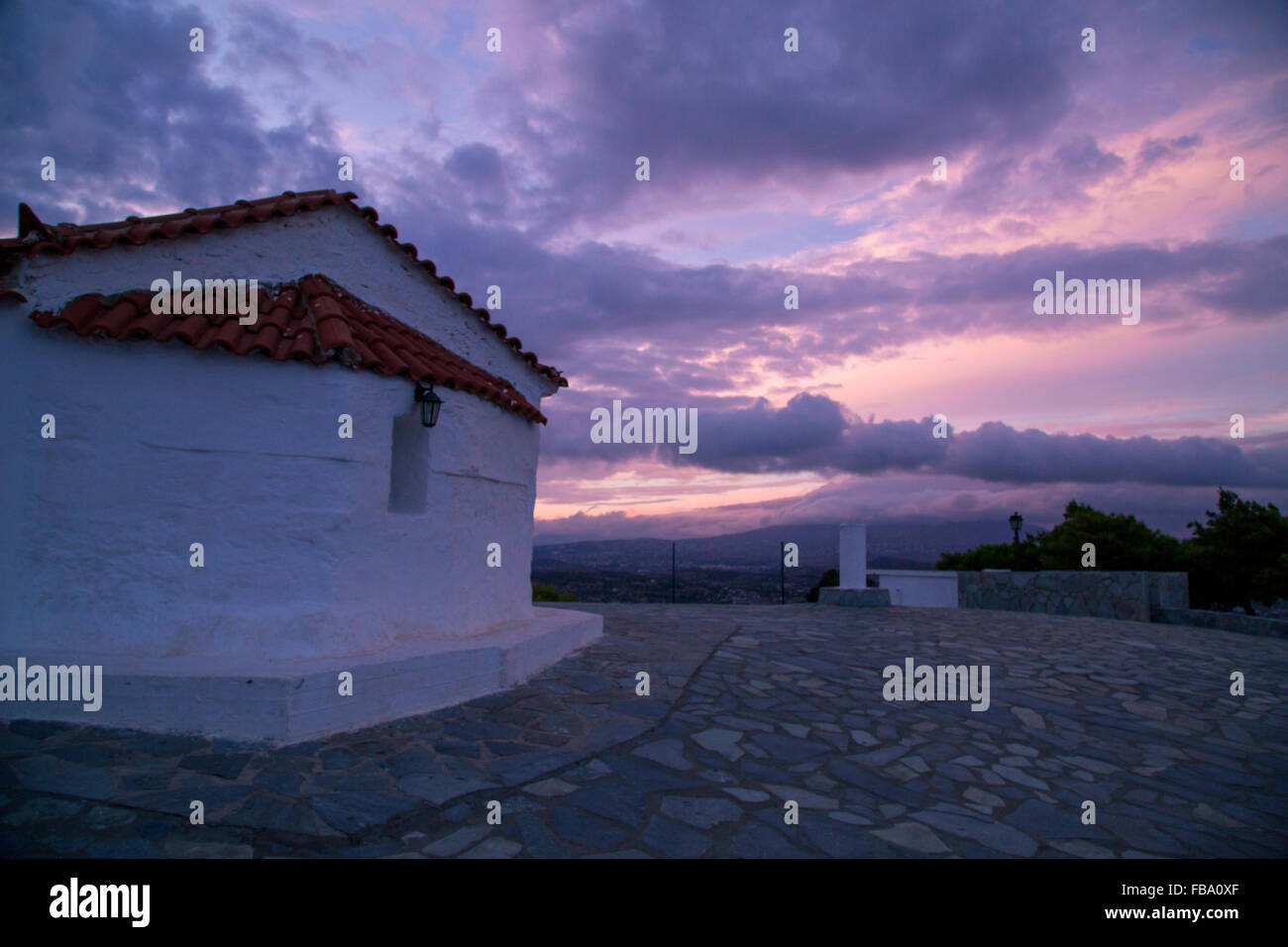 Sunset behind a small white Greek church. Stock Photo