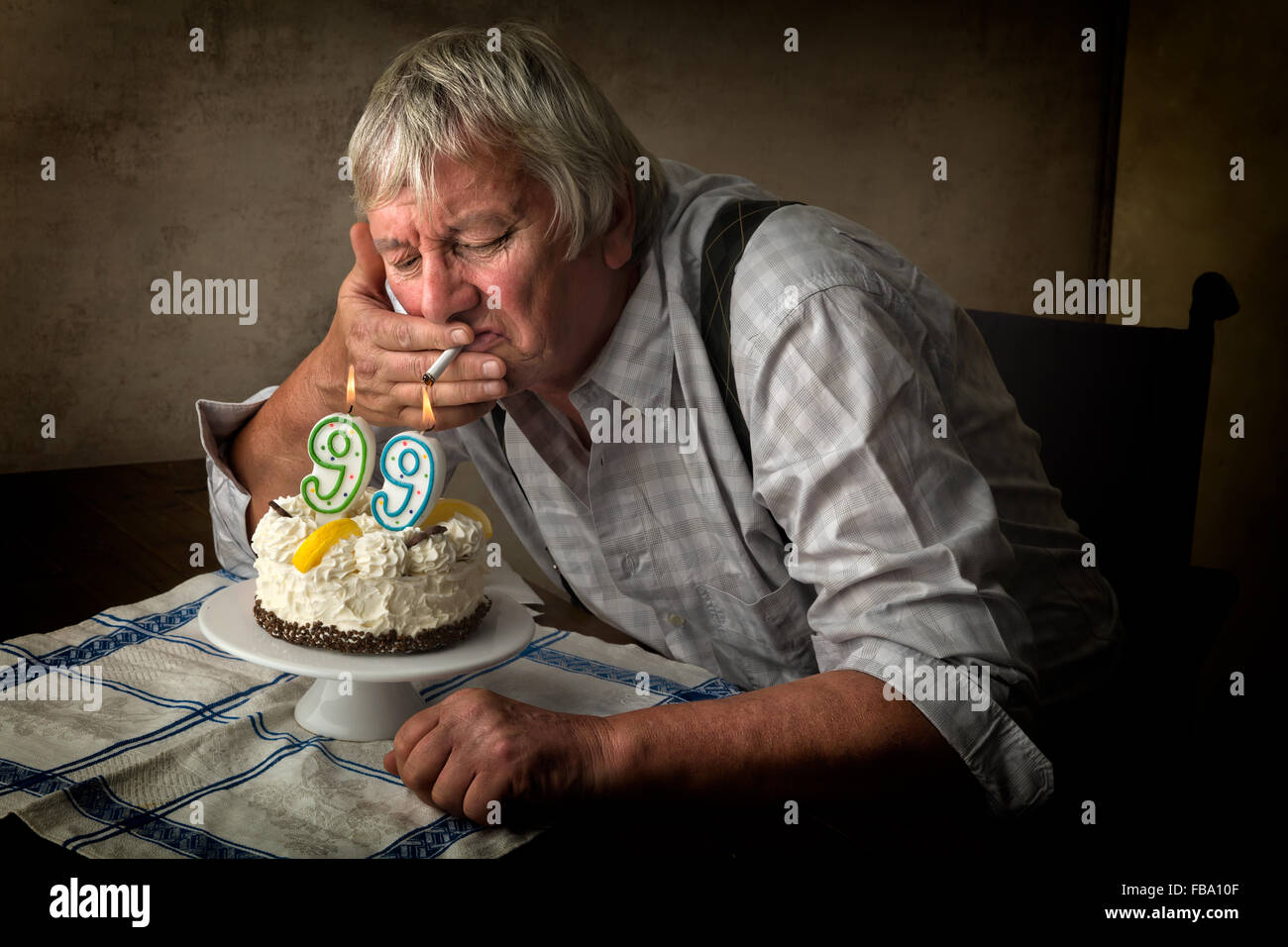 Old pensioner lighting his cigarette on his birthday cake Stock Photo