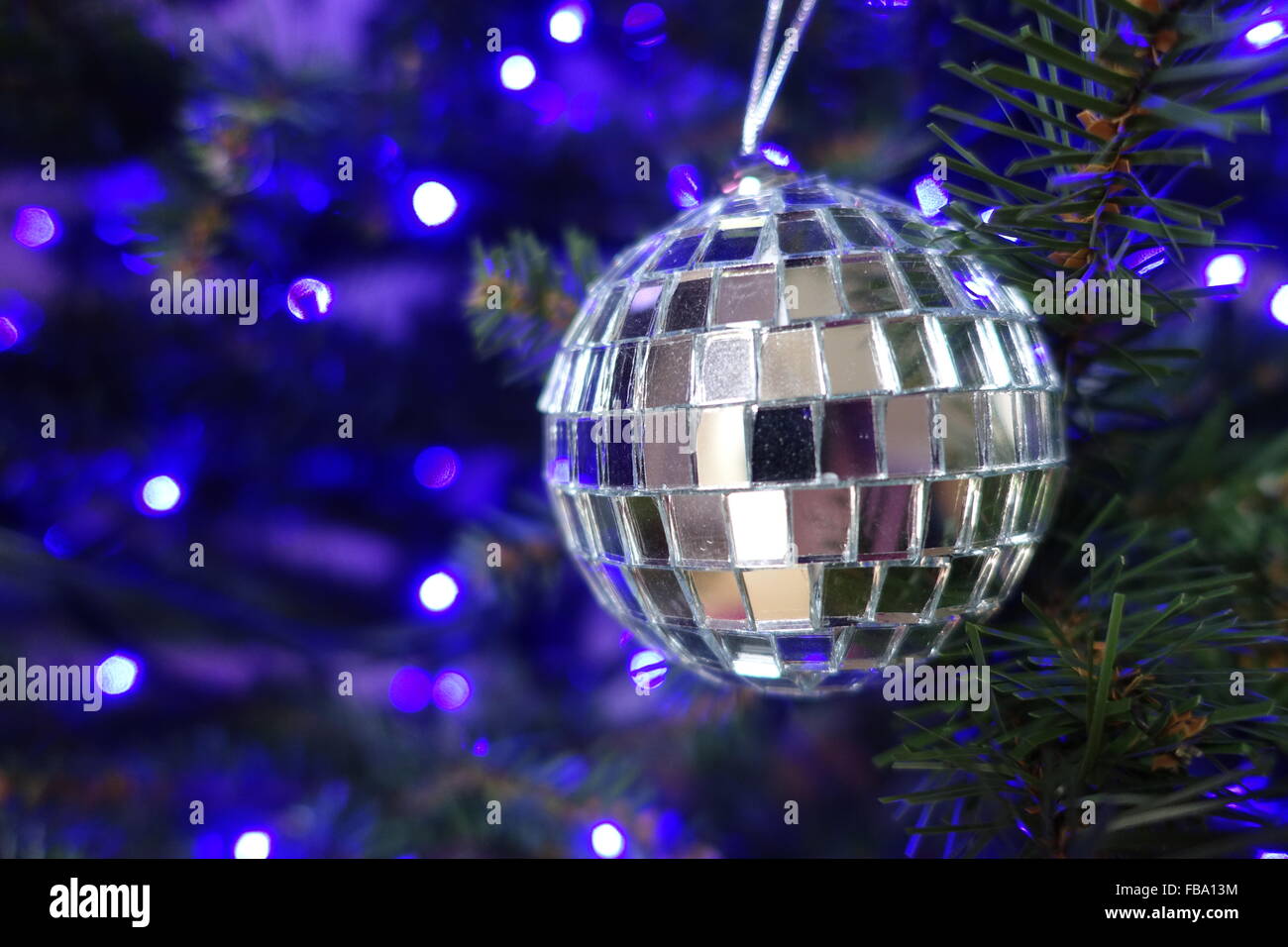 Silver ball hanging on a Christmas tree with blue lights in the ...