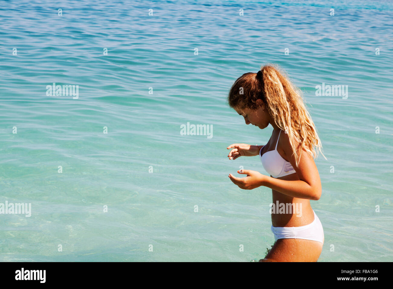 Blond young girl entering the sea Stock Photo