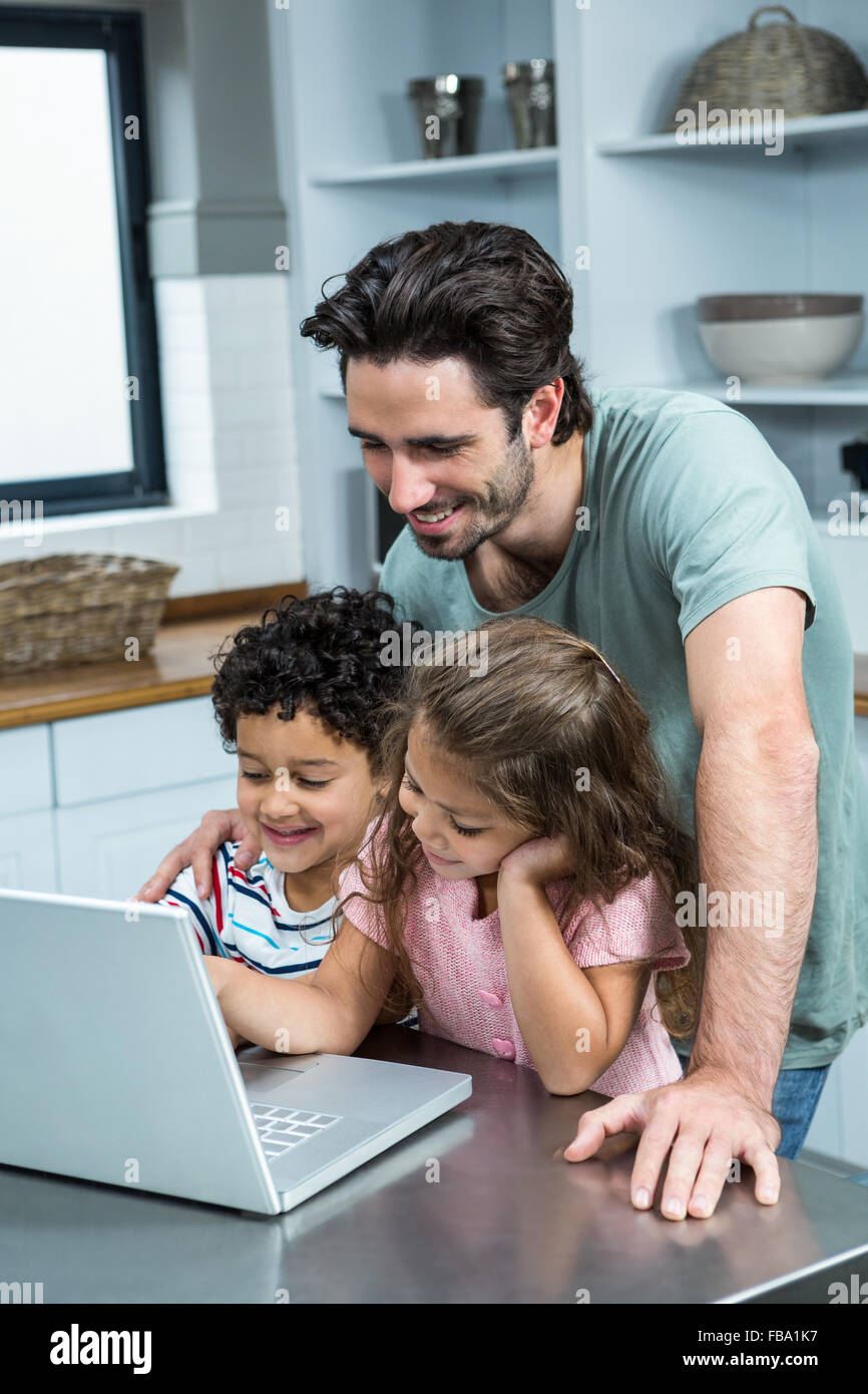 Smiling father using laptop with his children Stock Photo - Alamy