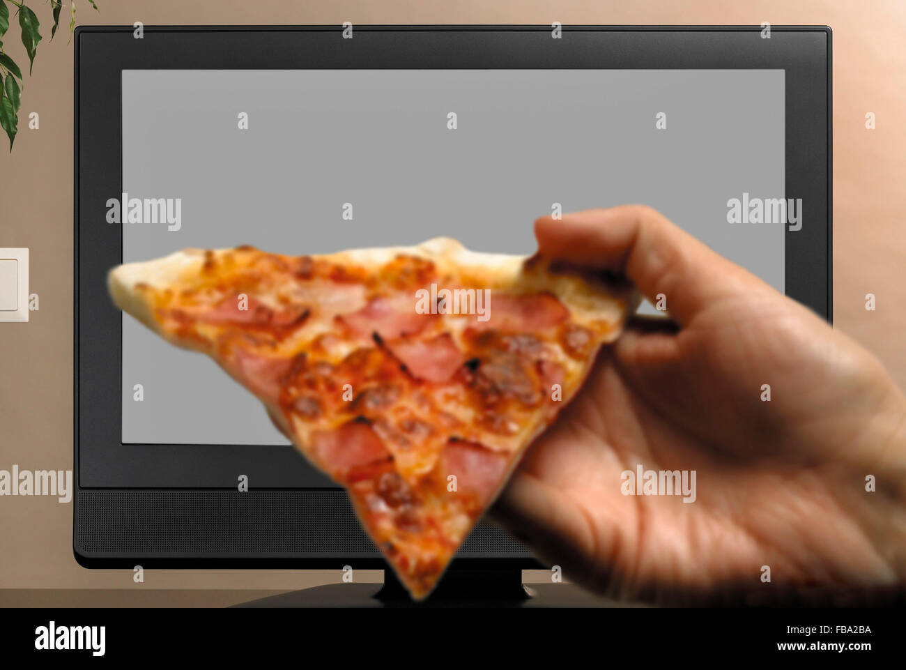 Man hand with pizza slice watching TV copy space Stock Photo