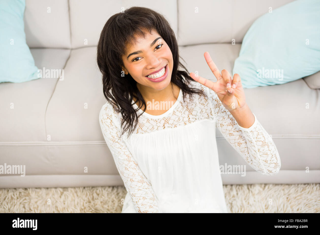 Casual smiling woman gesturing peace sign Stock Photo