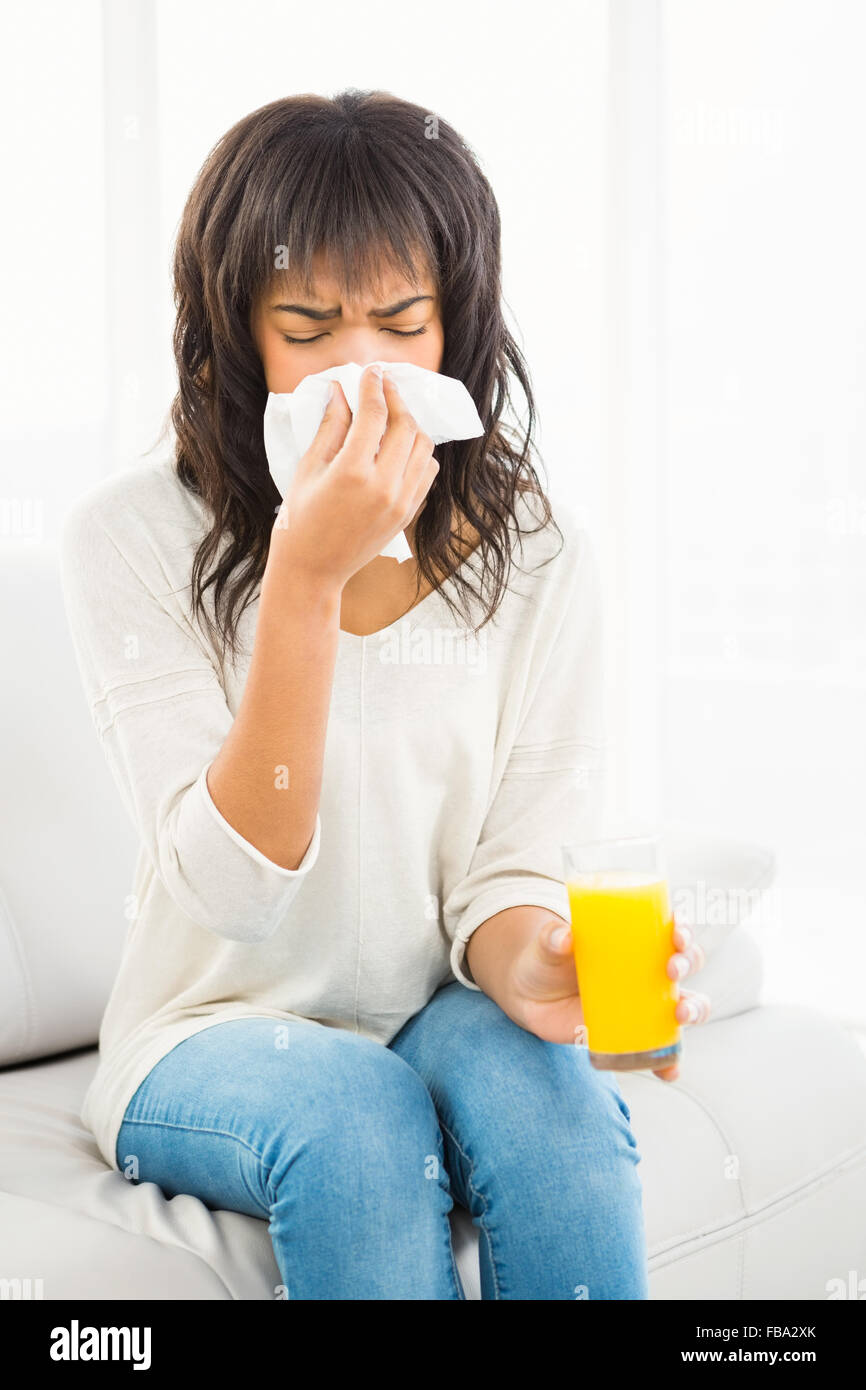 Pretty woman sneezing on couch Stock Photo