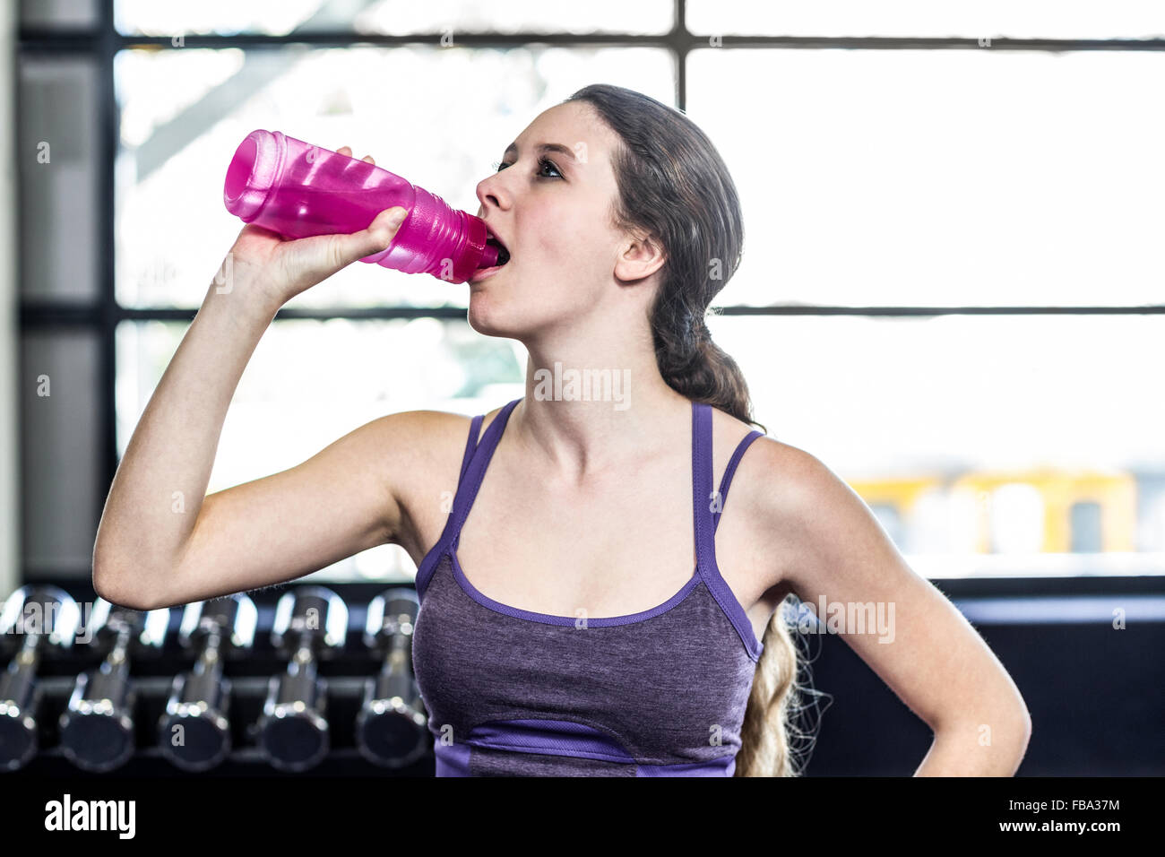 Thirsty woman drinking water on exercise ball Stock Photo