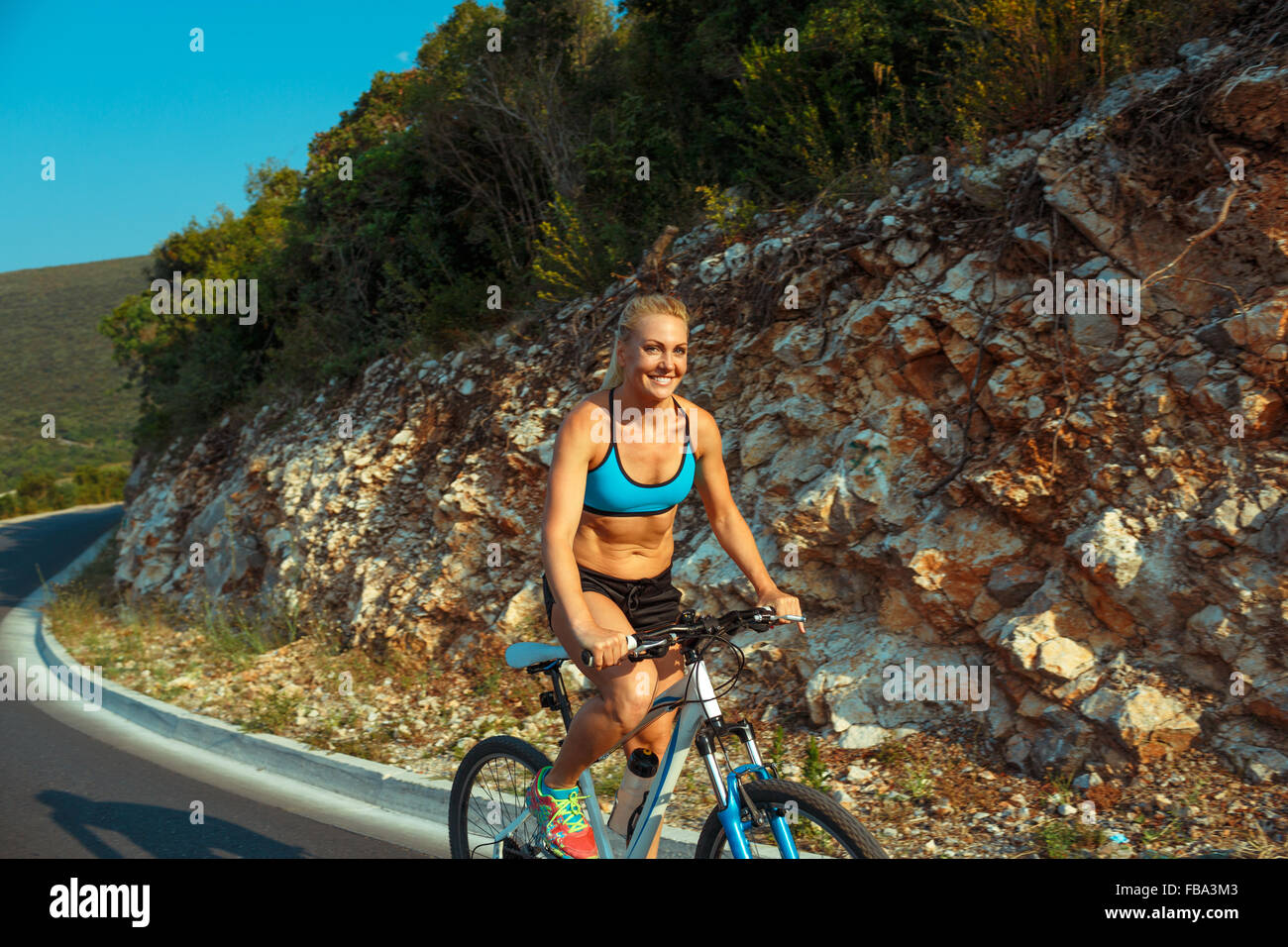 Woman cyclist riding a bike on a mountain road Stock Photo