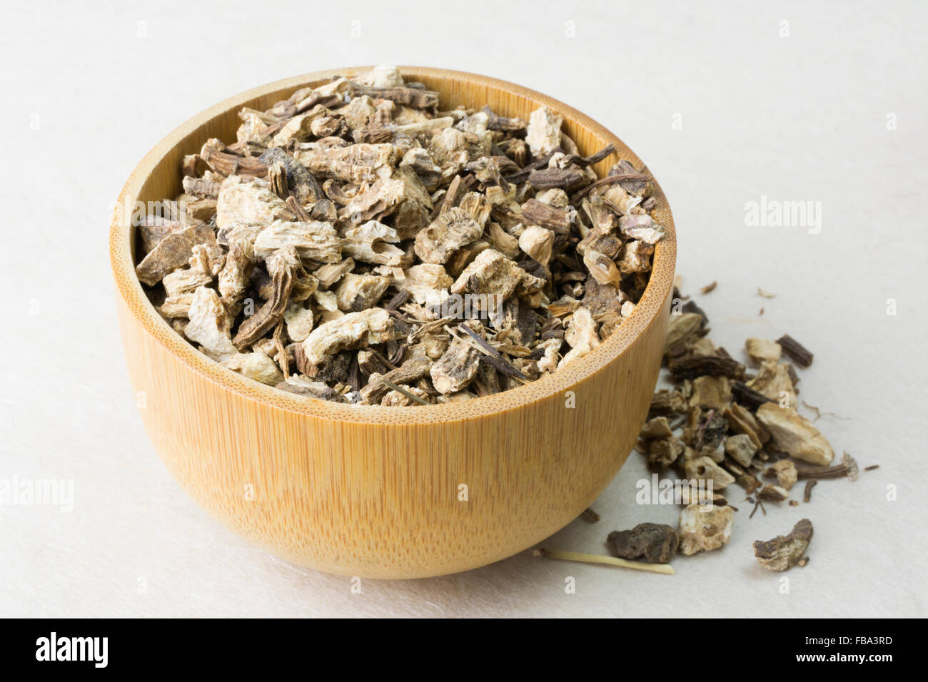 Chopped Angelica Root (Angelica archangelica) in a wooden cup Stock Photo