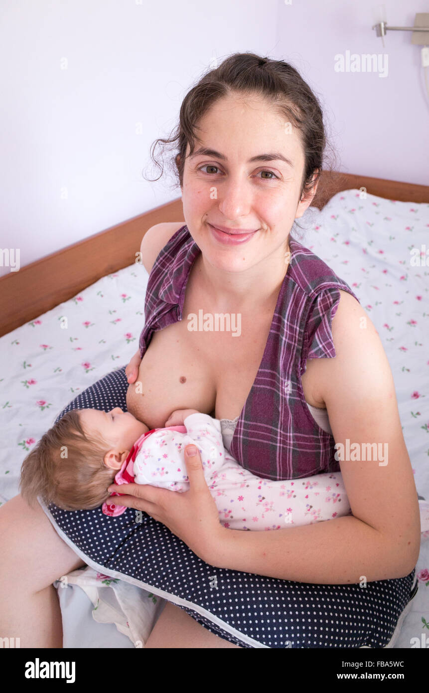Happy mother breastfeeding newborn baby at home Stock Photo