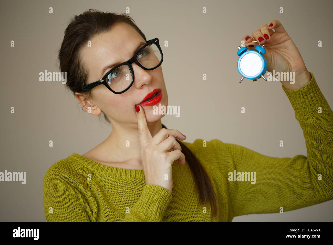 Little blue alarm clock in the hands of an emotional young woman, concept of saving time Stock Photo