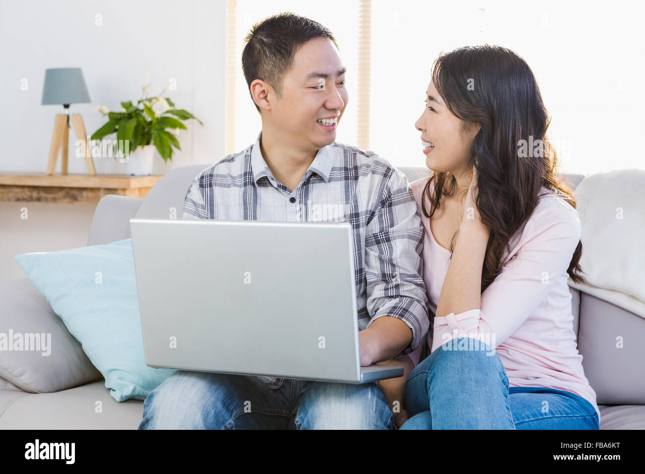 Happy young couple using laptop Stock Photo - Alamy