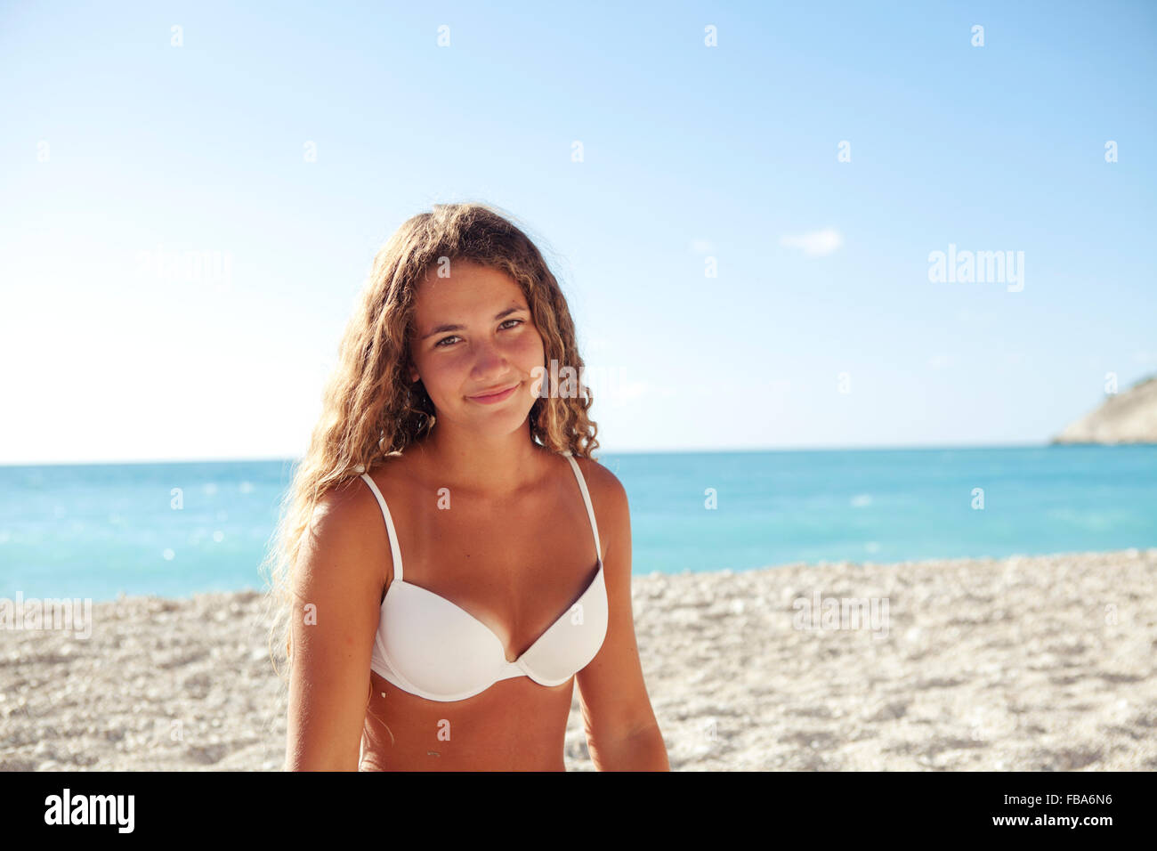 Young blond girl smiling on a white beach wearing white bikini. Myrtos beach Lixouri, Kefalonia, Ionian Islands Greece Stock Photo
