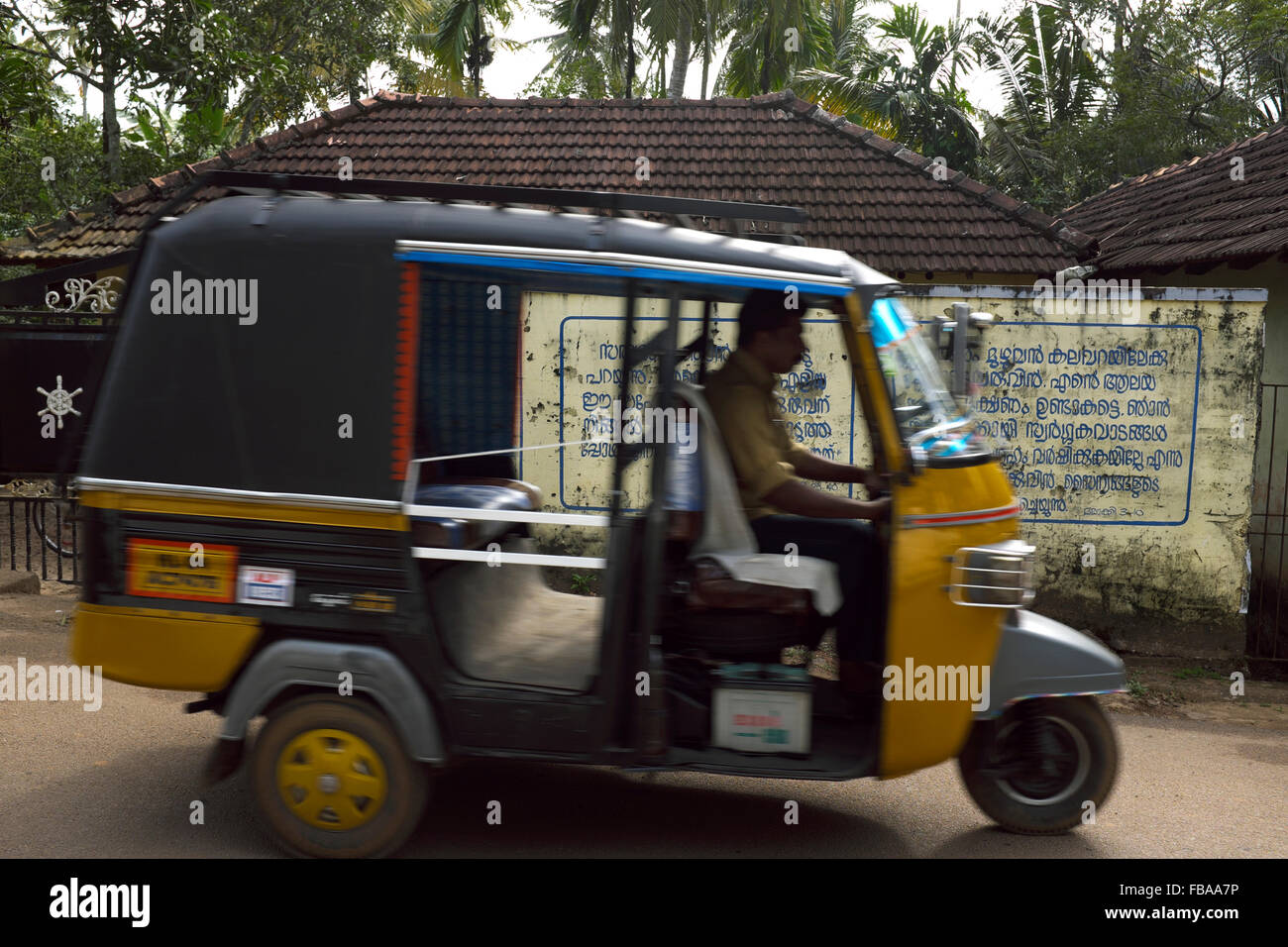 An auto-rickshaw passes a sign on a wall in Allepuzha (Alleppey), Kerala, India Stock Photo