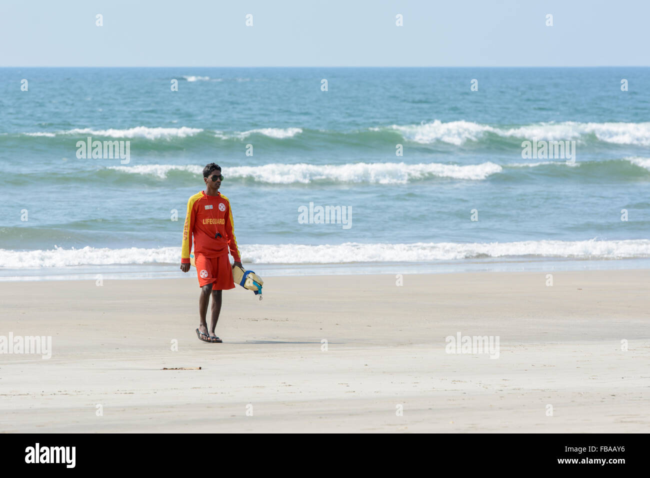 A young surf rescue life guard patrols the shore-line on Mandrem beach, North Goa, India Stock Photo