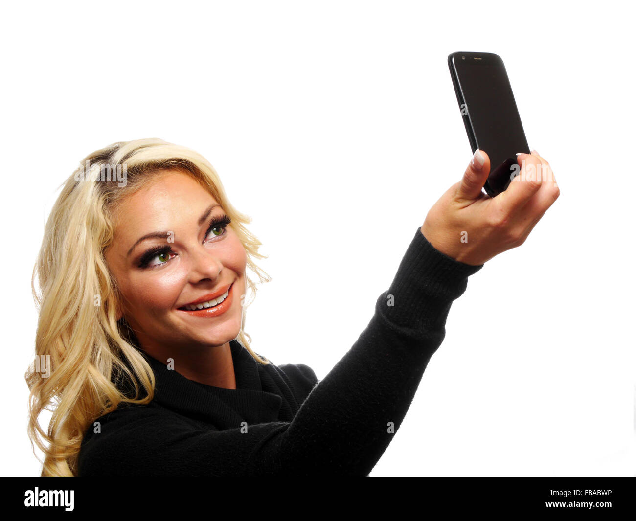 A attractive blond woman is taking her picture with her cell phone camera. Stock Photo
