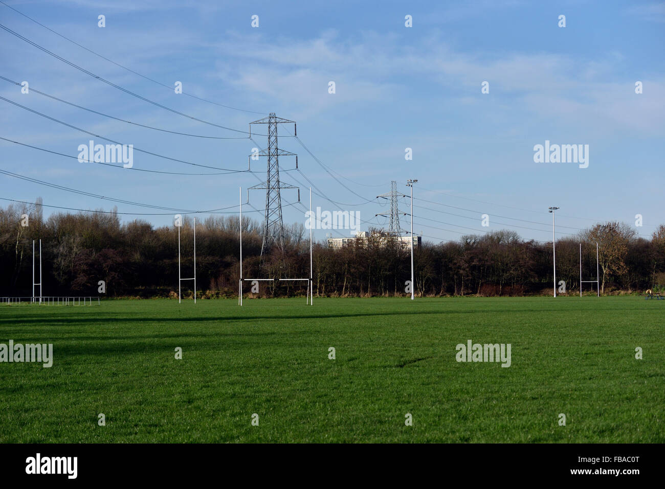 a sports ground  lies underneath national grid pylons Stock Photo