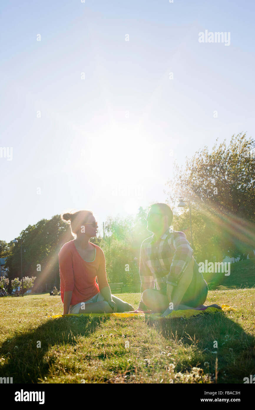 Finland, Uusimaa, Helsinki, Kaivopuisto, Young woman and man sitting in park on sunny day Stock Photo