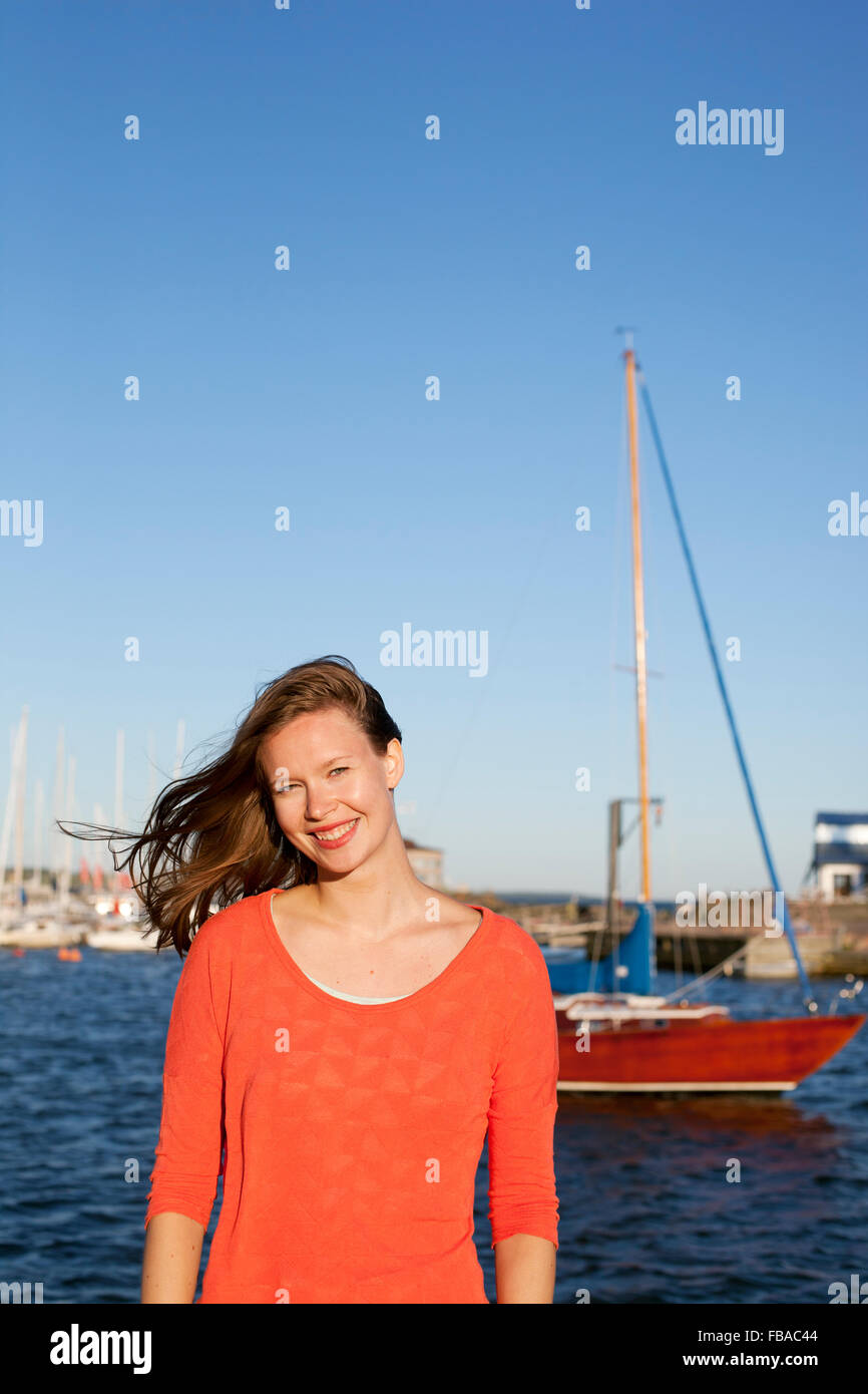 Finland, Uusimaa, Helsinki, Kaivopuisto, Portrait of smiling young woman with sea in background Stock Photo