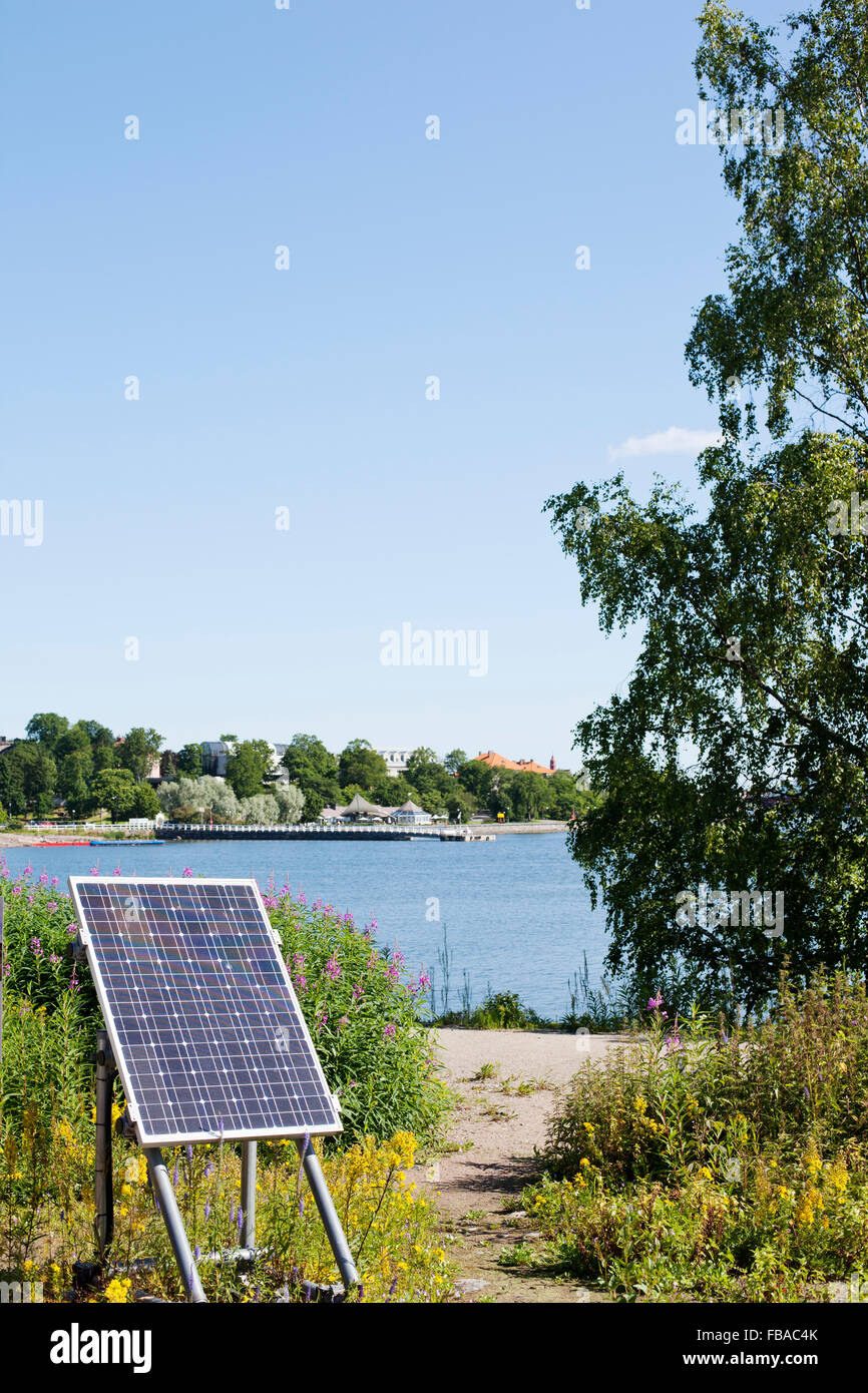 Finland, Uusimaa, Helsinki, Solar panel on grass and bay of water in background Stock Photo