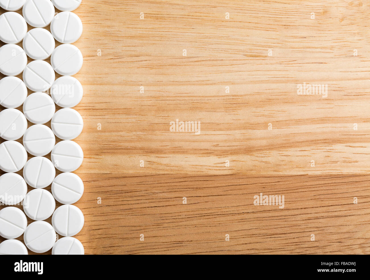 Border from white pills on a wooden background.Top view Stock Photo