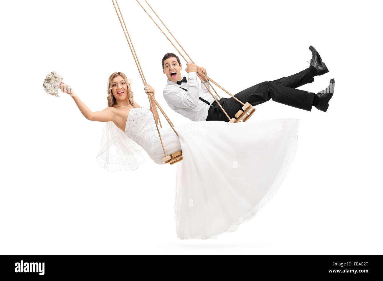 Studio shot of young groom and a bride swinging on wooden swings isolated on white background Stock Photo
