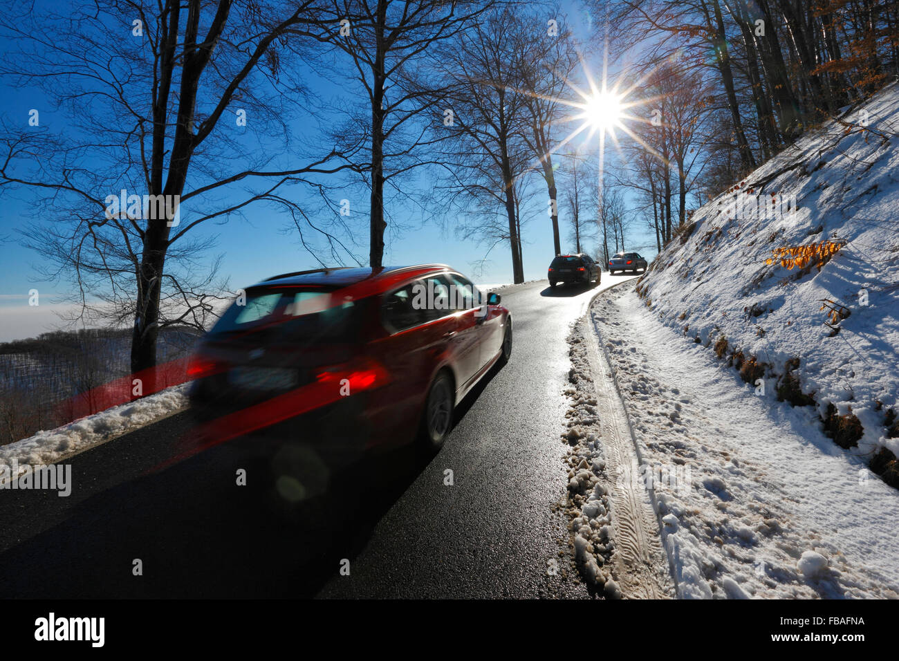 Road in winter with cars and sun beam in the sky Stock Photo