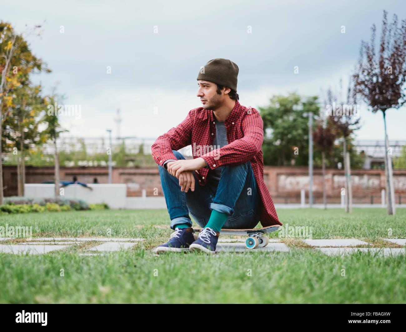 A guy sitting on his skateboard Stock Photo