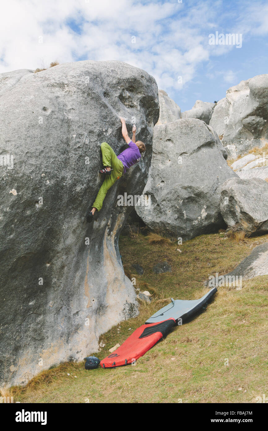 New Zealand, Castle Hill, Young man climbing up boulder with two crash