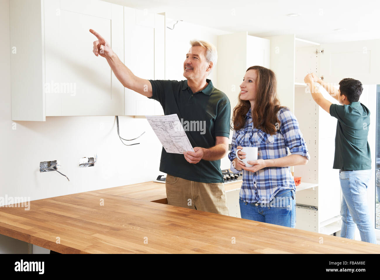 Woman With Carpenter Looking At Plans For New Kitchen Stock Photo