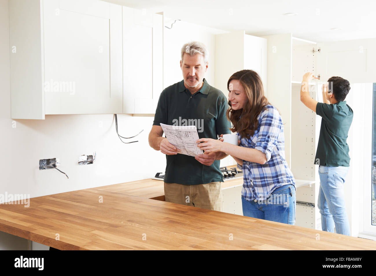 Woman With Carpenter Looking At Plans For New Kitchen Stock Photo