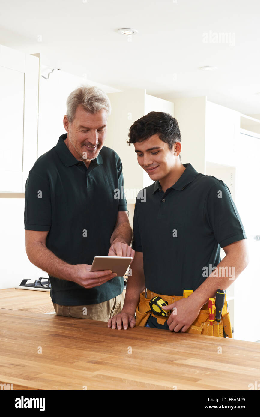 Carpenter And Apprentice With Digital Tablet Fitting Luxury Kitchen Stock Photo